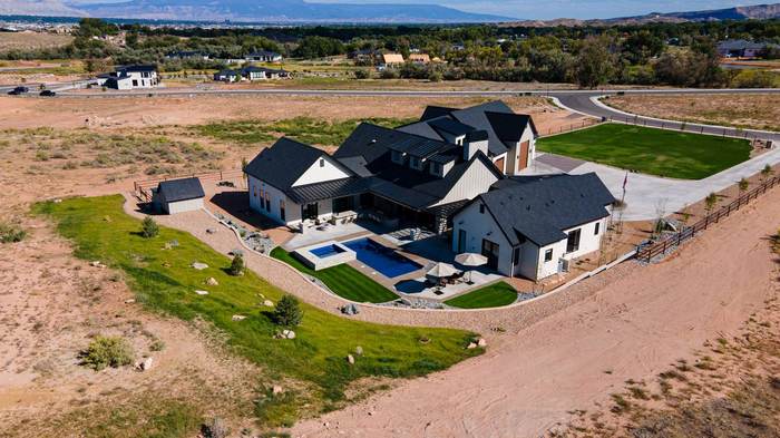 Wide rear aerial showing pool, patios, and Grand Valley beyond